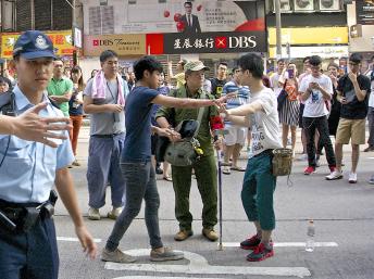 铜锣湾占领区警方已经加派警力防止黑帮捣乱，但仍有一些反占中人士，如图中身穿绿色军服手臂缠上“为人民服务”布条的男子，与学生口角。（郑汉良摄）