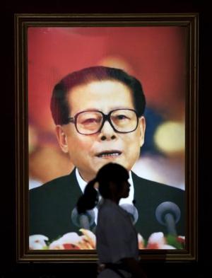 一位妇女走过江泽民画像.当局否认江已经去世.