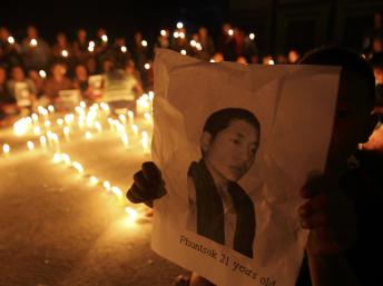 尼泊尔藏人举行烛光晚会为自焚身亡的四川格尔登寺僧人祈祷，图为一个藏人儿童高举着不久前身亡的僧人的照片。