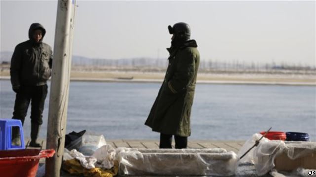 中国渔民在丹东的河边卖鱼，河对岸是朝鲜边境城镇新义州。中国东北受朝鲜之害(2013年2月7日)